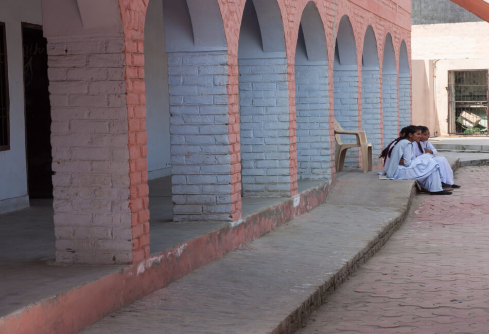 Three adolescent girls sitting outside their school corridor